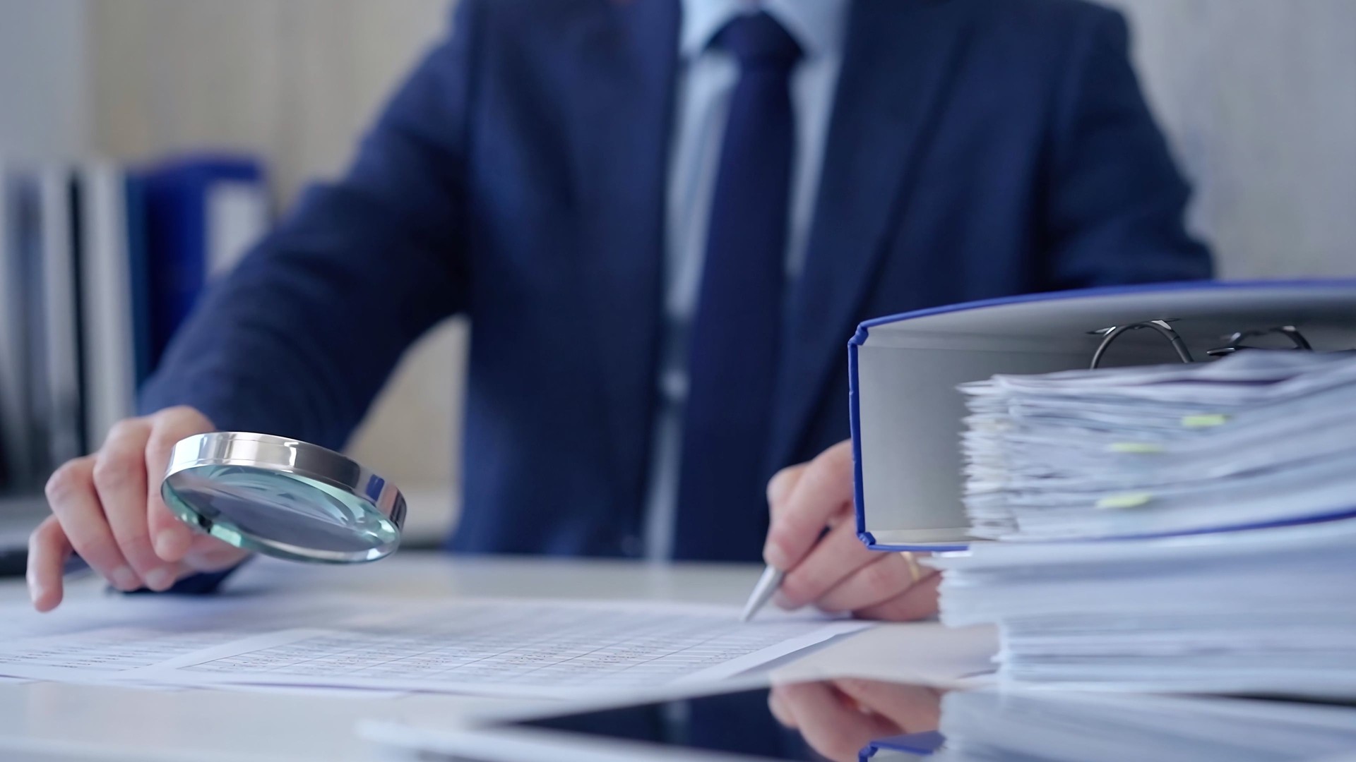 Businessman is carefully examining financial documents with a magnifying glass, highlighting the importance of thorough analysis in business. Audit and taxes